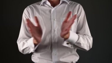 Beyaz gömlekli bir adam ellerini çırpıyor. koyu bir arkaplanda