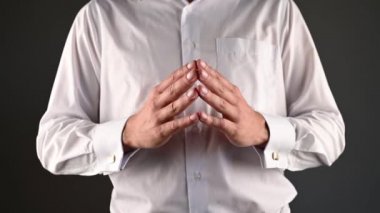 Beyaz gömlekli bir adam ellerini kullanarak yardım eder.