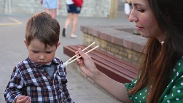 Een moeder en kind eten sushi op straat — Stockvideo
