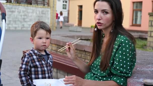 Mutter mit Baby isst Sushi auf der Straße — Stockvideo