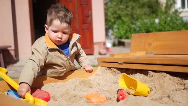 Un bambino passa del tempo a giocare nella sabbiera. Gioca fuori — Video Stock