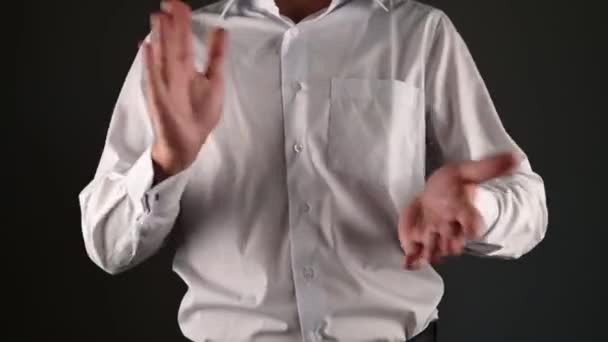 Een man in een wit shirt klapt in zijn handen. op een donkere achtergrond — Stockvideo