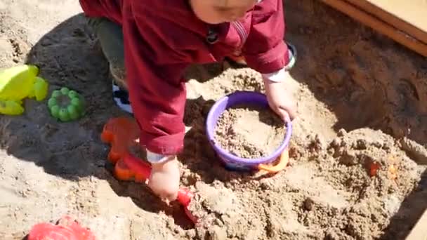 Un niño pasa tiempo jugando en la caja de arena. Juega afuera. — Vídeos de Stock