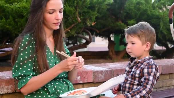 Matka z dzieckiem jedzą sushi na ulicy na ulicy — Wideo stockowe