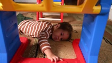 Çocuk masanın altında yatıyor. Evde saklambaç oynayın.