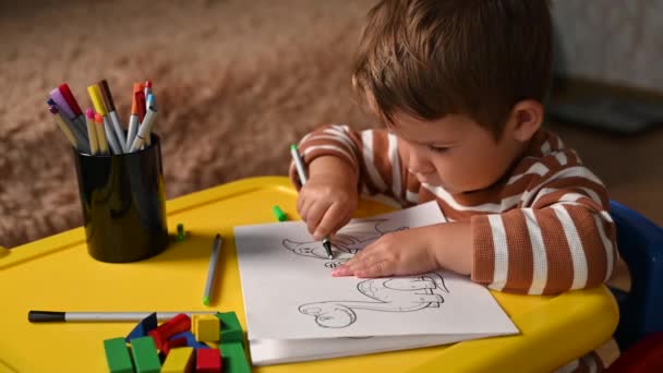 Dítě kreslí samostatně u stolu. Zábavné vzdělávací hry — Stock video
