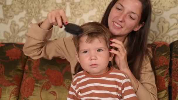 Mamá peinando bebé 1-2 años de edad. Cuidado del cabello del bebé en casa. — Vídeos de Stock