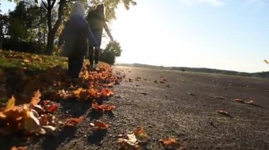 Annesiyle birlikte sonbahar parkında koşan bir çocuk. Yüksek kaliteli video