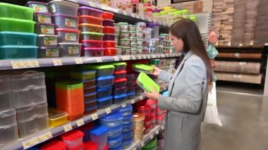 Kız markette yiyecek depolamak için yeni plastik kaplar seçiyor..