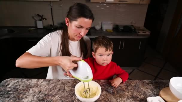 Anya és gyermek keveri a tésztát egy keverővel. Kiváló minőségű videó — Stock videók