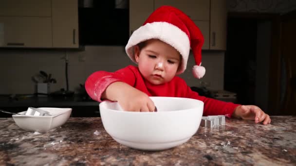 Un niño con un sombrero de Navidad está cocinando. Video de alta calidad — Vídeo de stock