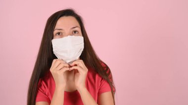 Pembe arka planda koruyucu maskeli bir kız. Yüksek kalite fotoğraf