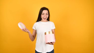 Kız sarı arka planda bir hediye kutusu açıyor. Yüksek kalite fotoğraf