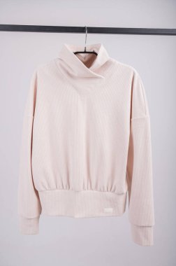 İzole edilmiş bir arkaplanda asılı bej bir ceket..