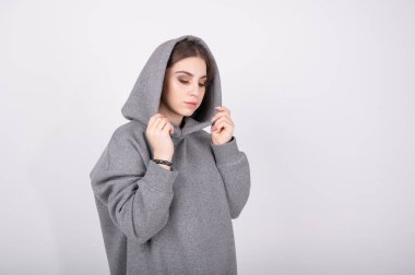 Kafasında kapüşon olan gri kazaklı genç bir kız. Yüksek kalite fotoğraf