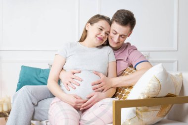 Genç baba müstakbel annenin karnına tutunuyor. 