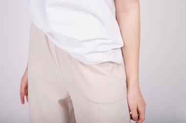 Beyaz tişörtlü ve açık renk pantolonlu kadın manzarası. Rahat kadın kıyafetleri, temel gardırop konsepti.