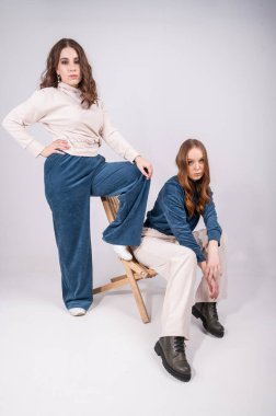 İki genç, şık kadın kameraya bakarken beyaz poz veriyor. Kadın kapsül gardırobu konsepti. Yüksek kalite fotoğraf