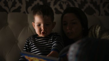 Çocuklu anne yatmadan önce karanlıkta bir kitap okudu. Yüksek kalite fotoğraf