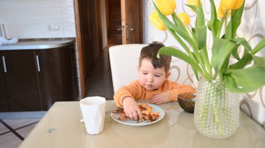 Çocuk masada kendi başına yemek yiyor. Yüksek kalite fotoğraf