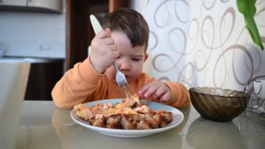 Çocuk masada kendi başına yemek yiyor. Yüksek kaliteli video