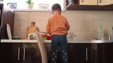 Çocuk mutfakta yemek hazırlıyor, arkadan bakıyor. Yüksek kaliteli video
