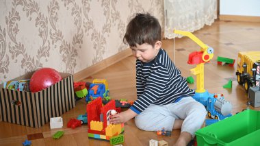 Yerde oturan çocuk inşaatçıyı oynuyor. Yüksek kalite fotoğraf