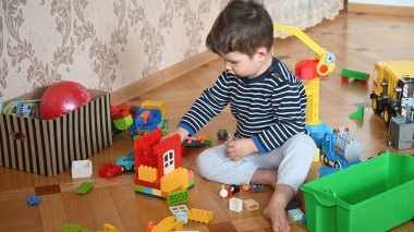 Yerde oturan çocuk inşaatçıyı oynuyor. Yüksek kalite fotoğraf