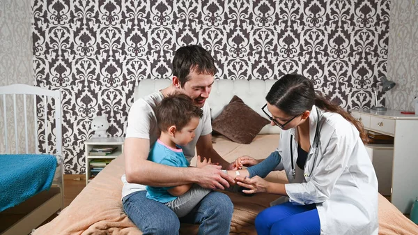 The doctor treats the child's leg at home. High quality photo
