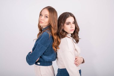 Kıvırcık saçlı, sıradan kıyafetler giyen iki hoş görünümlü beyaz kadın portresi, kızlar sırtüstü dururlar. Yüksek kalite fotoğraf