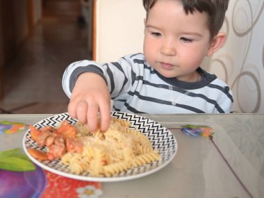 Çocuk sebzeli İtalyan makarnası yiyor.