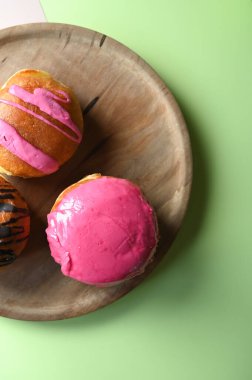 Pastel yeşil arka planda, ahşap bir tabakta jöleli donutların üst görüntüsü, metin için boş alanı olan üst manzara. Yüksek kalite fotoğraf