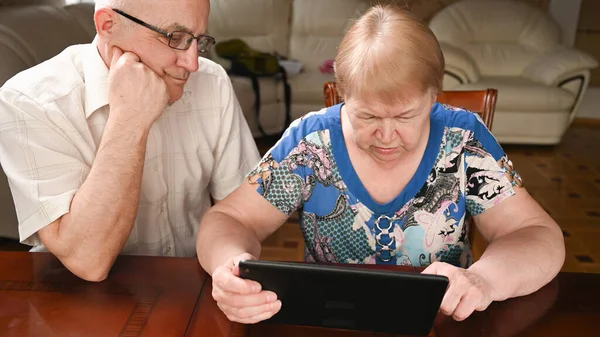 An elderly couple use modern gadgets to surf the Internet.