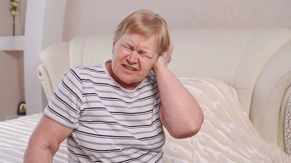 Elderly woman on bed with ear pain.