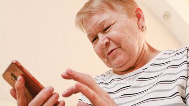 Elinde telefon olan yaşlı bir kadın, alt manzaralı..