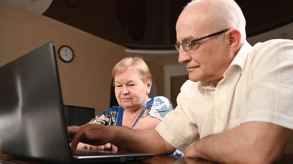 An elderly couple use modern gadgets to surf the Internet