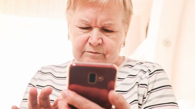 Evde cep telefonu olan yaşlı bir kadın..