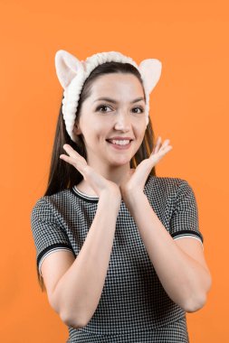 Turuncu arka planda kulakları olan genç bir kız.. 