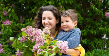 Kıvırcık saçlı genç anne ve elinde çiçeklerle bir çocuk.. 