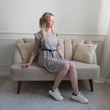 Yazlık elbiseli bir kadın kanepede oturuyor.. 