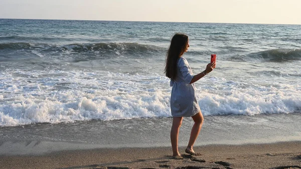 年轻女子为了留念而给大海拍照 — 图库照片