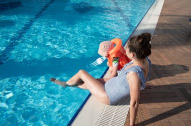 Havuzun yanında can yeleği giymiş bir çocuk. 