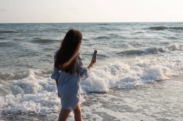 年轻女子在大海的背景下拍照 — 图库照片