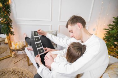 Hamile kadın kocasına ultrason görüntüsü gösteriyor. Birbirine aşık bir çift bebek bekliyor..