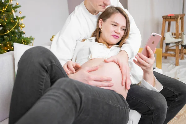 Mutlu genç çift cep telefonunda vakit geçiriyor. Evde Noel mutluluğu - sörf ve alışveriş.