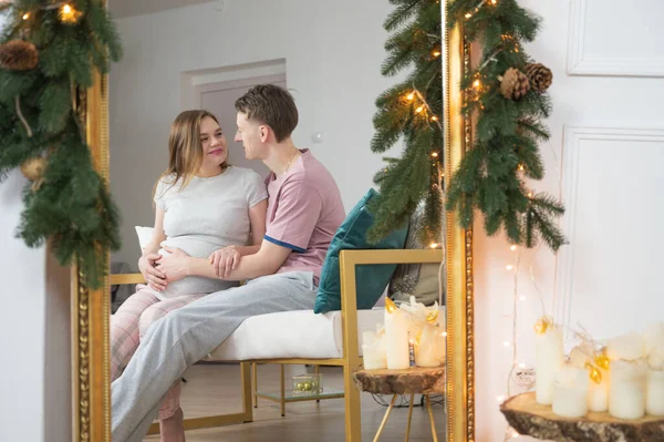 Aynadaki genç hamile çift. Noel süsleri. Hamilelik, kış tatili ve insanların konsepti.