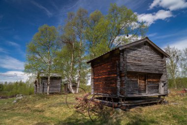 Tjamotis, Lapland, İsveç 'te güneşli bir yaz sabahı tarihi bir saman tırmığıyla eski ahşap sami deposu.