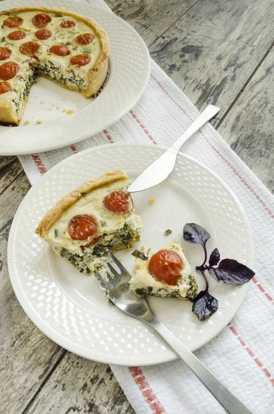 Stuk taart met cherry tomaten, kaas en uien op wit bord — Stockfoto