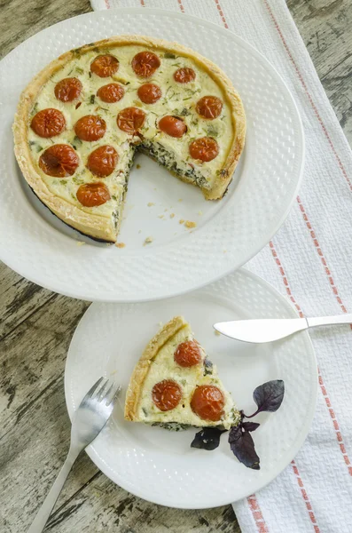Пирог с помидорами черри, сыром и луком на белой тарелке — стоковое фото