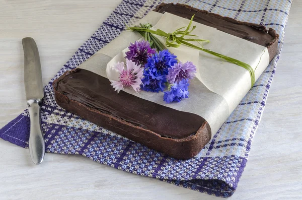 Čokoládový dortík s halva, zdobený chrpy, poblíž nůž — Stock fotografie